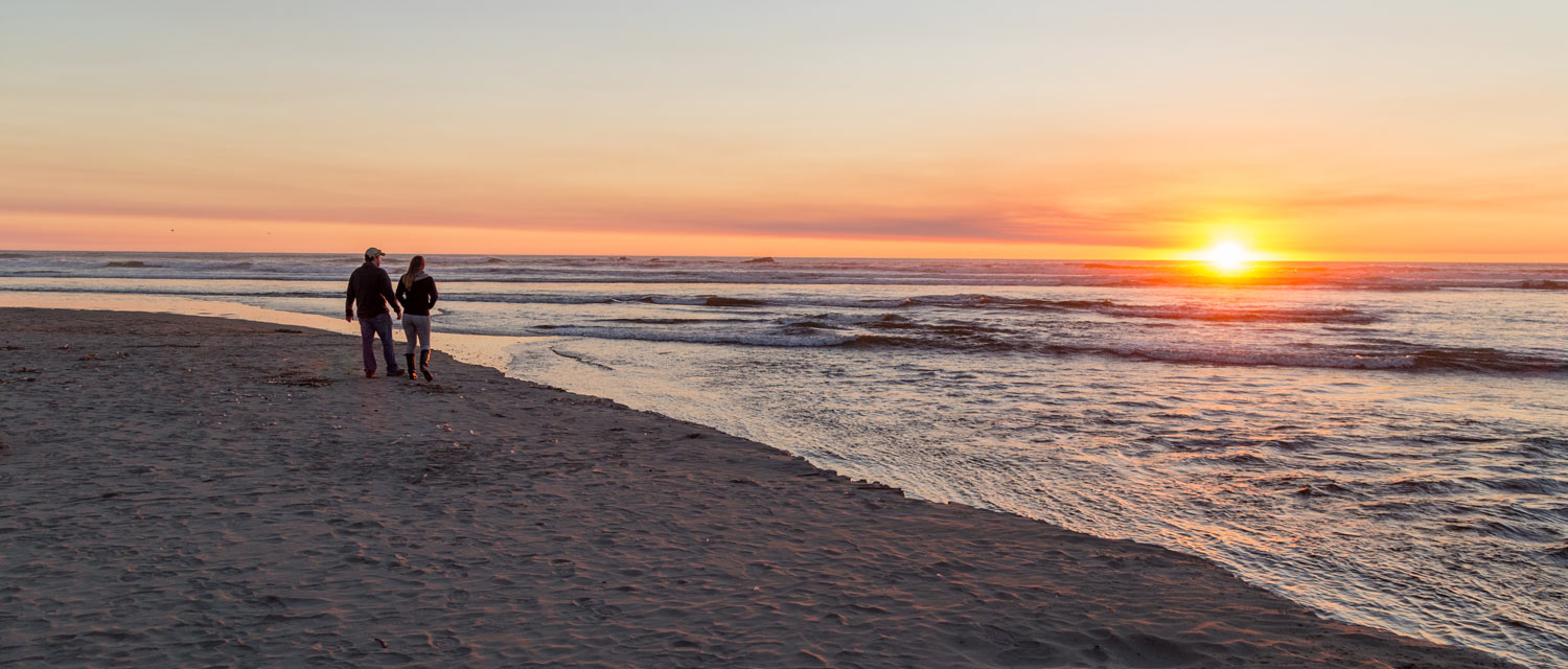 A couple stands on Kalaloch Beach and admires the vibrant sunset